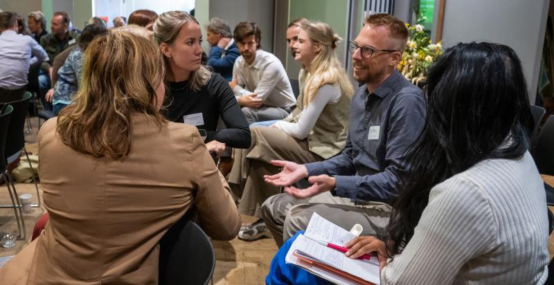 Groepje mensen met elkaar in gesprek tijdens een congres.