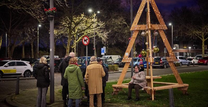 Een aantal Rotterdammers komen samen bij een circulaire kerstboom van hergebruikt hout.
