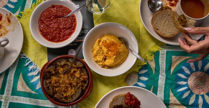 Op een tafel staan een aantal bakjes met dips van bijvoorbeeld olijven.